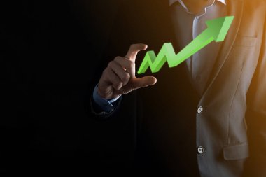 İş adamı artan ekran grafiği, pozitif büyüme ikonu okları üzerinde duruyor. Yaratıcı iş grafiğine yükselen oklarla işaret ediyor. Finansal, ticari büyüme kavramı.