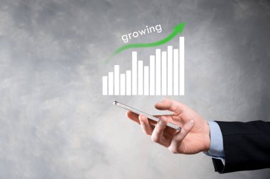 Holografik grafikler ve borsa istatistikleri tutan işadamı kâr elde ediyor. Büyüme planlama ve iş stratejisi kavramı. İyi ekonomi formunun dijital ekran görüntüsü.