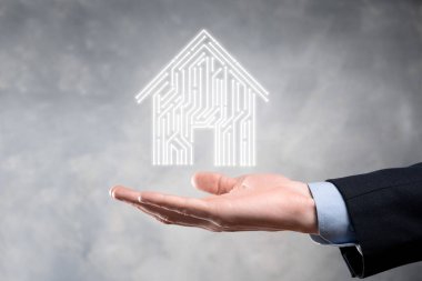 İş adamı ev ikonunu tutuyor. Marketin ev kontrollü, akıllı ev ve ev otomasyon uygulaması konsepti. PCB tasarımı ve akıllı telefonu olan kişi. Yenilik teknolojisi internet ağı kavramı