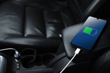 Cep telefonu, akıllı telefon, cep telefonu şarj edildi. Arabanın içinde USB şarj cihazıyla şarj edildi. modern siyah araba iç tasarımı.