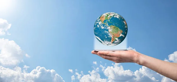 Hands holding a planet, earth on a background of nature blue sky with beautiful white clouds and sunlight.Sustain earth concept. Elements of this image furnished by NASA.