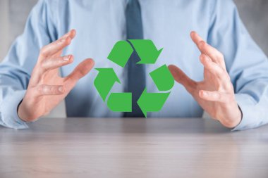 Takım elbiseli bir işadamı elinde bir geri dönüşüm simgesi tutuyor. Ekoloji, çevre ve koruma kavramı. Neon kırmızı mavi ışık.
