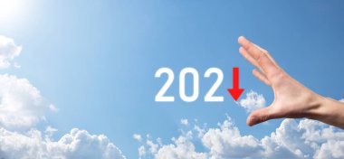 2021 yılında iş negatif büyüme planı. İşadamı planında ve işinde olumsuz göstergelerde artış, iş kavramlarını düşürme. Gökyüzü arka planında elle tutunma.