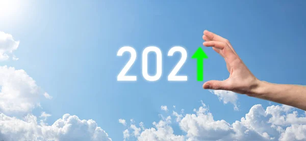 Hand hold 2021 positive icon on sky background.Plan business positive growth in year 2021 concept. Businessman plan and increase of positive indicators in his business, Growing up business concepts