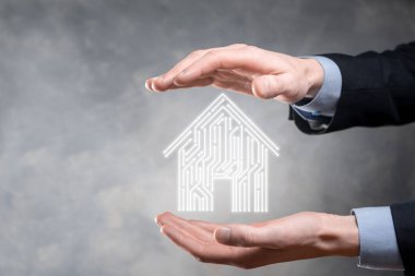 İş adamı ev ikonunu tutuyor. Marketin ev kontrollü, akıllı ev ve ev otomasyon uygulaması konsepti. PCB tasarımı ve akıllı telefonu olan kişi. Yenilik teknolojisi internet ağı kavramı