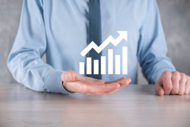 İş adamı elinde pozitif kar artışı olan bir grafik tutuyor. Grafik büyümesi ve grafik artışı işlerinde olumlu göstergeler. Daha kârlı ve büyüyen