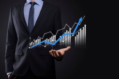 Holografik grafikler ve borsa istatistikleri tutan işadamı kâr elde ediyor. Büyüme planlama ve iş stratejisi kavramı. İyi ekonomi formunun dijital ekran görüntüsü
