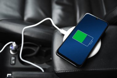 Cep telefonu, akıllı telefon, cep telefonu şarj edildi. Arabanın içinde USB şarj cihazıyla şarj edildi. modern siyah araba iç tasarımı.