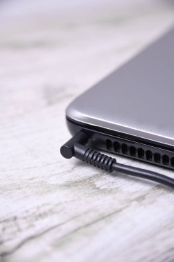 Laptop, bilgisayar duvarın yanındaki bir masada 220 voltluk bir prizden şarj oluyor. Enerji, birikim