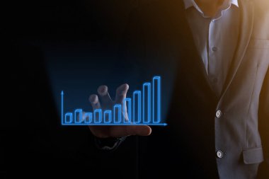 Holografik grafikler ve borsa istatistikleri tutan işadamı kâr elde ediyor. Büyüme planlama ve iş stratejisi kavramı. İyi ekonomi formunun dijital ekran görüntüsü