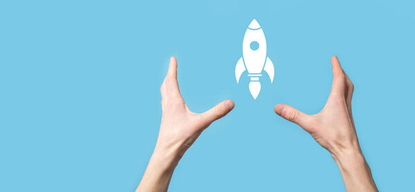 Male hand holding rocket icon that takes off, launch on blue background. rocket is launching and flying out, Business start up, Icon marketing on modern virtual interface.Start up concept