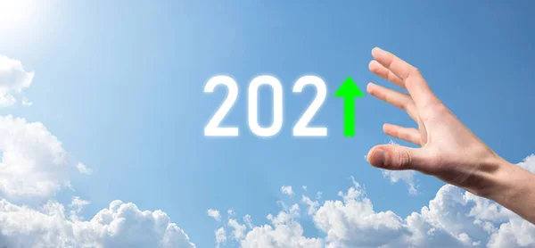 Hand hold 2021 positive icon on sky background.Plan business positive growth in year 2021 concept. Businessman plan and increase of positive indicators in his business, Growing up business concepts