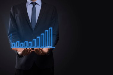 Holografik grafikler ve borsa istatistikleri tutan işadamı kâr elde ediyor. Büyüme planlama ve iş stratejisi kavramı. İyi ekonomi formunun dijital ekran görüntüsü