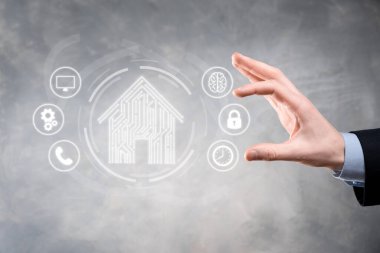 İş adamı ev ikonunu tutuyor. Marketin ev kontrollü, akıllı ev ve ev otomasyon uygulaması konsepti. PCB tasarımı ve akıllı telefonu olan kişi. Yenilik teknolojisi internet ağı kavramı