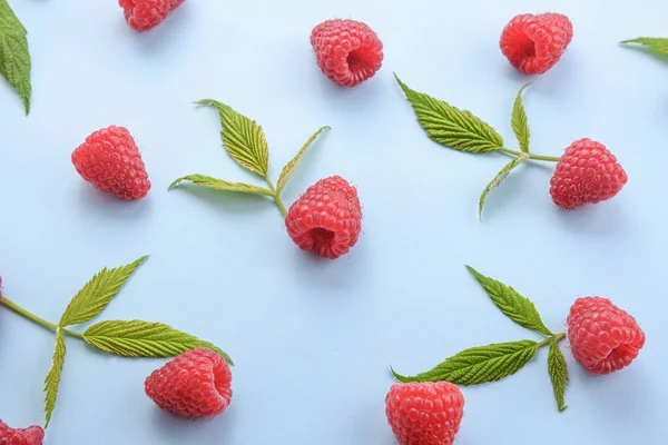 Pattern of raspberry and green leaves on blue background. Flat lay summer berries - red raspberries. Creative minimalism.