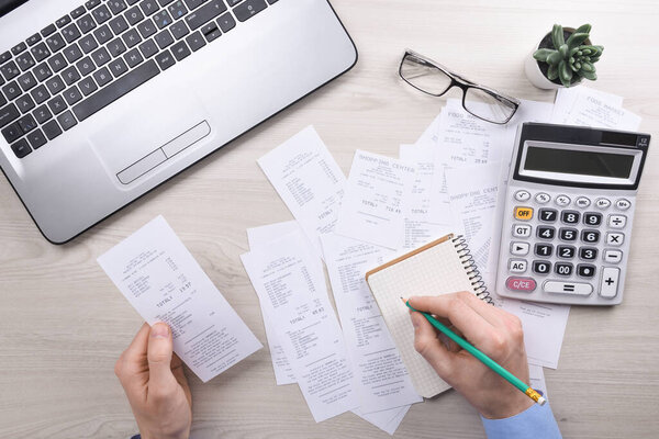 Unrecognizable businessman using calculator on desk office and writing make note with calculate about cost at home office. finance accounting concept. tax , shopping, cost management.