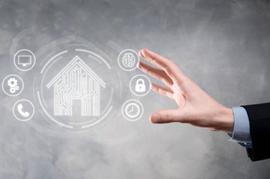 İş adamı ev ikonunu tutuyor. Marketin ev kontrollü, akıllı ev ve ev otomasyon uygulaması konsepti. PCB tasarımı ve akıllı telefonu olan kişi. Yenilik teknolojisi internet ağı kavramı
