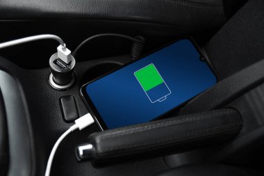 Cep telefonu, akıllı telefon, cep telefonu şarj edildi. Arabanın içinde USB şarj cihazıyla şarj edildi. modern siyah araba iç tasarımı.