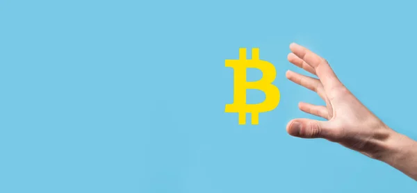 Male hand holding a bitcoin icon on blue background. Bitcoin Cryptocurrency Digital Bit Coin BTC Currency Technology Business Internet Concept