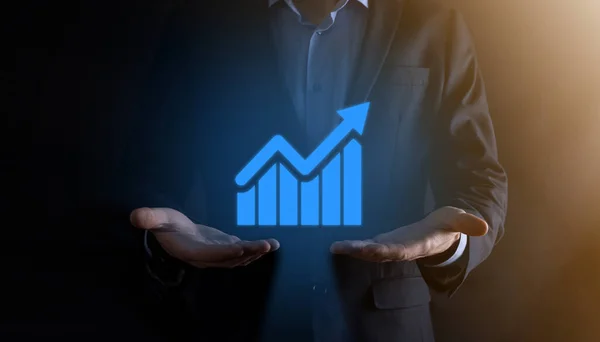 Businessman man holding a graph with positive profits growth. plan graph growth and increase of chart positive indicators in his business.more profitable and growing