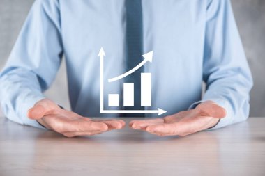 İş adamı artan ekran grafiği, pozitif büyüme ikonu okları üzerinde duruyor. Yaratıcı iş grafiğine yükselen oklarla işaret ediyor. Finansal, ticari büyüme kavramı.