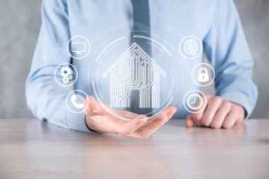 İş adamı ev ikonunu tutuyor. Marketin ev kontrollü, akıllı ev ve ev otomasyon uygulaması konsepti. PCB tasarımı ve akıllı telefonu olan kişi. Yenilik teknolojisi internet ağı kavramı