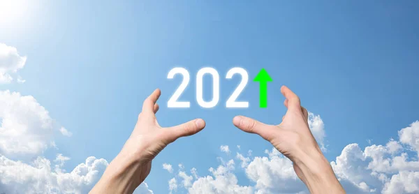 Hand hold 2021 positive icon on sky background.Plan business positive growth in year 2021 concept. Businessman plan and increase of positive indicators in his business, Growing up business concepts