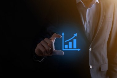 İş adamı elinde pozitif kar artışı olan bir grafik tutuyor. Grafik büyümesi ve grafik artışı işlerinde olumlu göstergeler. Daha kârlı ve büyüyen