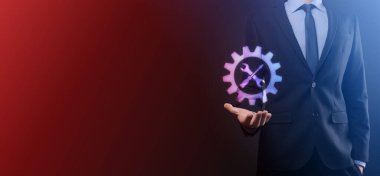 İş adamı araç gereç simgesini araçlarla tutuyor. Dişliler. Hedef odaklı dijital diyagram, grafik arayüzleri, sanal UI ekranı, netwoork bağlantıları kavramı