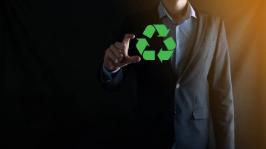 Takım elbiseli bir işadamı elinde bir geri dönüşüm simgesi tutuyor. Ekoloji, çevre ve koruma kavramı. Neon kırmızı mavi ışık.