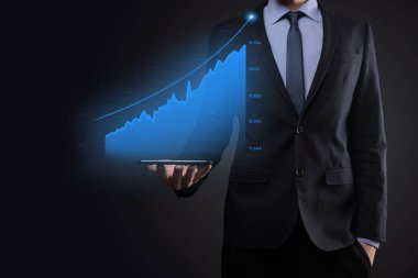 Holografik grafikler ve borsa istatistikleri tutan işadamı kâr elde ediyor. Büyüme planlama ve iş stratejisi kavramı. İyi ekonomi formunun dijital ekran görüntüsü