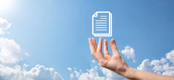Male hand holding a document icon on blue background. Document Management Data System Business Internet Technology Concept. Corporate data management system DMS.