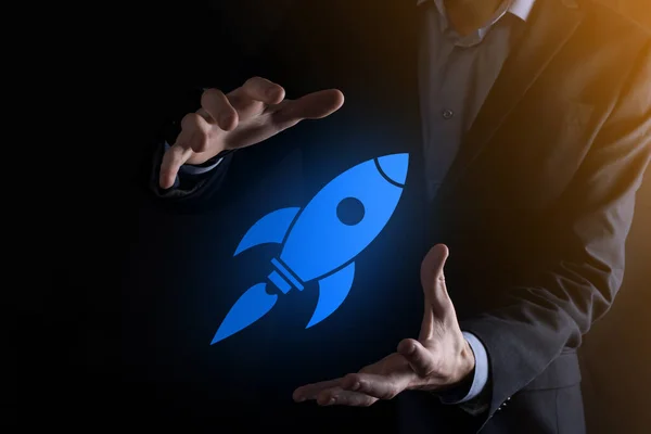 Start up concept with businessman holding abstract digital rocket icon rocket is launching and soar flying.