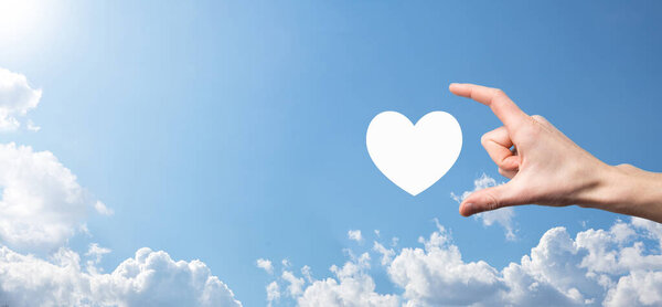 Male hand holding heart , like icon on blue background. Kindness, charity, pure love and compassion concept.Banner with copy space.