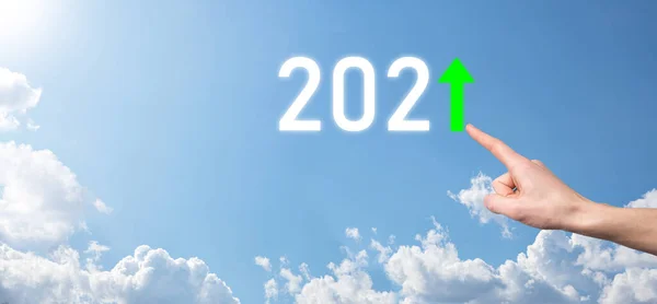 Hand hold 2021 positive icon on sky background.Plan business positive growth in year 2021 concept. Businessman plan and increase of positive indicators in his business, Growing up business concepts