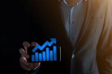 İş adamı elinde pozitif kar artışı olan bir grafik tutuyor. Grafik büyümesi ve grafik artışı işlerinde olumlu göstergeler. Daha kârlı ve büyüyen