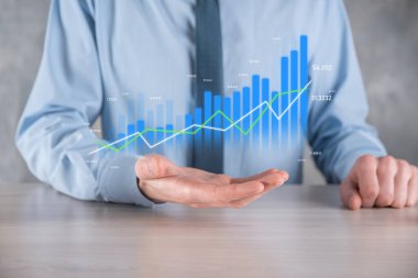 İş adamı elinde pozitif kar artışı olan bir grafik tutuyor. Grafik büyümesi ve grafik artışı işlerinde olumlu göstergeler. Daha kârlı ve büyüyen.