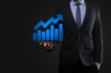İş adamı artan ekran grafiği, pozitif büyüme ikonu okları üzerinde duruyor. Yaratıcı iş grafiğine yükselen oklarla işaret ediyor. Finansal, ticari büyüme kavramı.