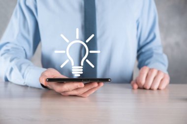 Elinde ampul olan takım elbiseli bir iş adamı. Elinde parlak bir fikir simgesi tutuyor. Metin için bir yer ile.