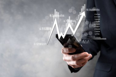 İş adamı satış verilerini ve ekonomik büyüme grafiğini elinde tutuyor. İş planlama ve strateji. Takas ticareti analiz ediliyor. Finansal ve bankacılık. Teknoloji dijital pazarlama. Kâr ve büyüyen plan.