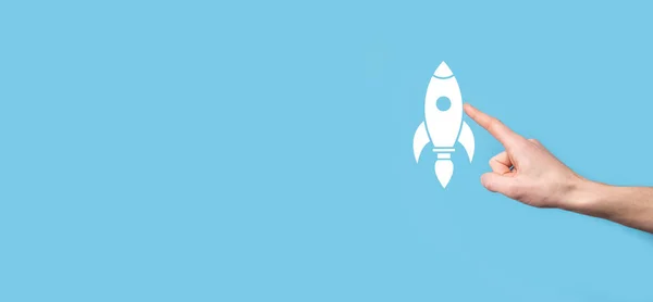 Male hand holding rocket icon that takes off, launch on blue background. rocket is launching and flying out, Business start up, Icon marketing on modern virtual interface.Start up concept