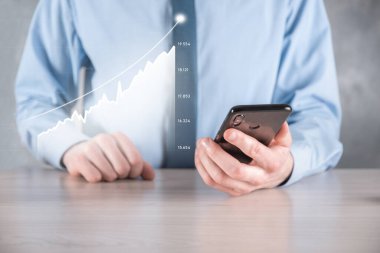 İş adamı elinde pozitif kar artışı olan bir grafik tutuyor. Grafik büyümesi ve grafik artışı işlerinde olumlu göstergeler. Daha kârlı ve büyüyen.