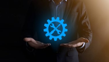 İş adamı araç gereç simgesini araçlarla tutuyor. Dişliler. Hedef odaklı dijital diyagram, grafik arayüzleri, sanal UI ekranı, netwoork bağlantıları kavramı