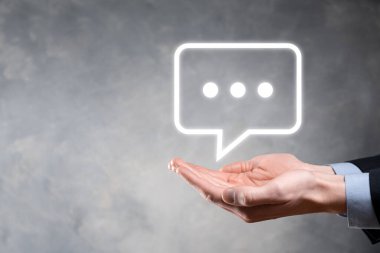 Elinde mesaj ikonu tutan bir iş adamı, elinde baloncuklu konuşma tebligat işareti var. Sohbet simgesi, SMS simgesi, yorum simgesi, konuşma baloncukları.