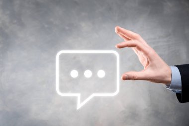 Elinde mesaj ikonu tutan bir iş adamı, elinde baloncuklu konuşma tebligat işareti var. Sohbet simgesi, SMS simgesi, yorum simgesi, konuşma baloncukları.