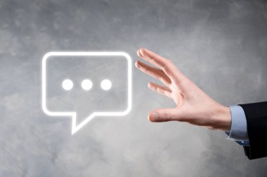 Elinde mesaj ikonu tutan bir iş adamı, elinde baloncuklu konuşma tebligat işareti var. Sohbet simgesi, SMS simgesi, yorum simgesi, konuşma baloncukları.