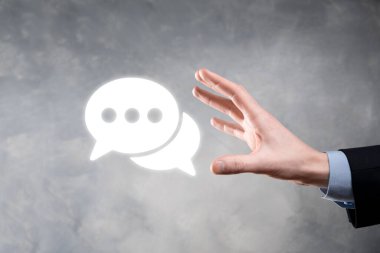 Elinde mesaj ikonu tutan bir iş adamı, elinde baloncuklu konuşma tebligat işareti var. Sohbet simgesi, SMS simgesi, yorum simgesi, konuşma baloncukları.
