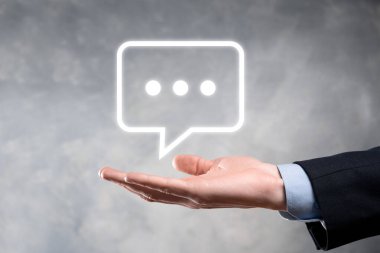 Elinde mesaj ikonu tutan bir iş adamı, elinde baloncuklu konuşma tebligat işareti var. Sohbet simgesi, SMS simgesi, yorum simgesi, konuşma baloncukları.