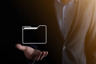 İş adamı dizin simgesini tutuyor. Belge Yönetim Sistemi veya modern bilgisayar bilişim danışmanı tarafından kurulmuş DMS yönetici dosyaları ve kurumsal dosyaları arıyor. İş işleme