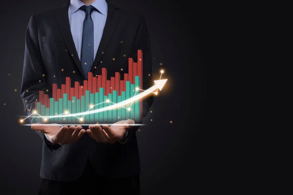 Business man holding holographic graphs and stock market statistics gain profits. Concept of growth planning and business strategy. Display of good economy form digital screen